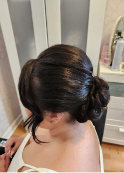 A woman's sleek bun wedding hairstyle from the left.