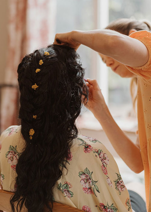 A woman putting makeup on a bride.