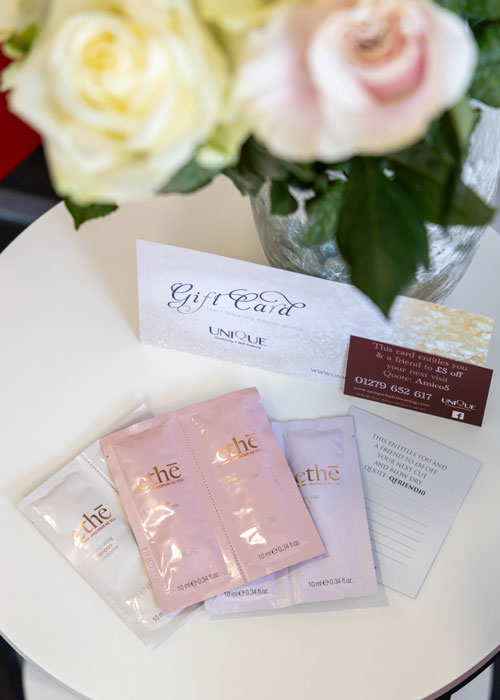 Hair product samples next to flowers on a table.
