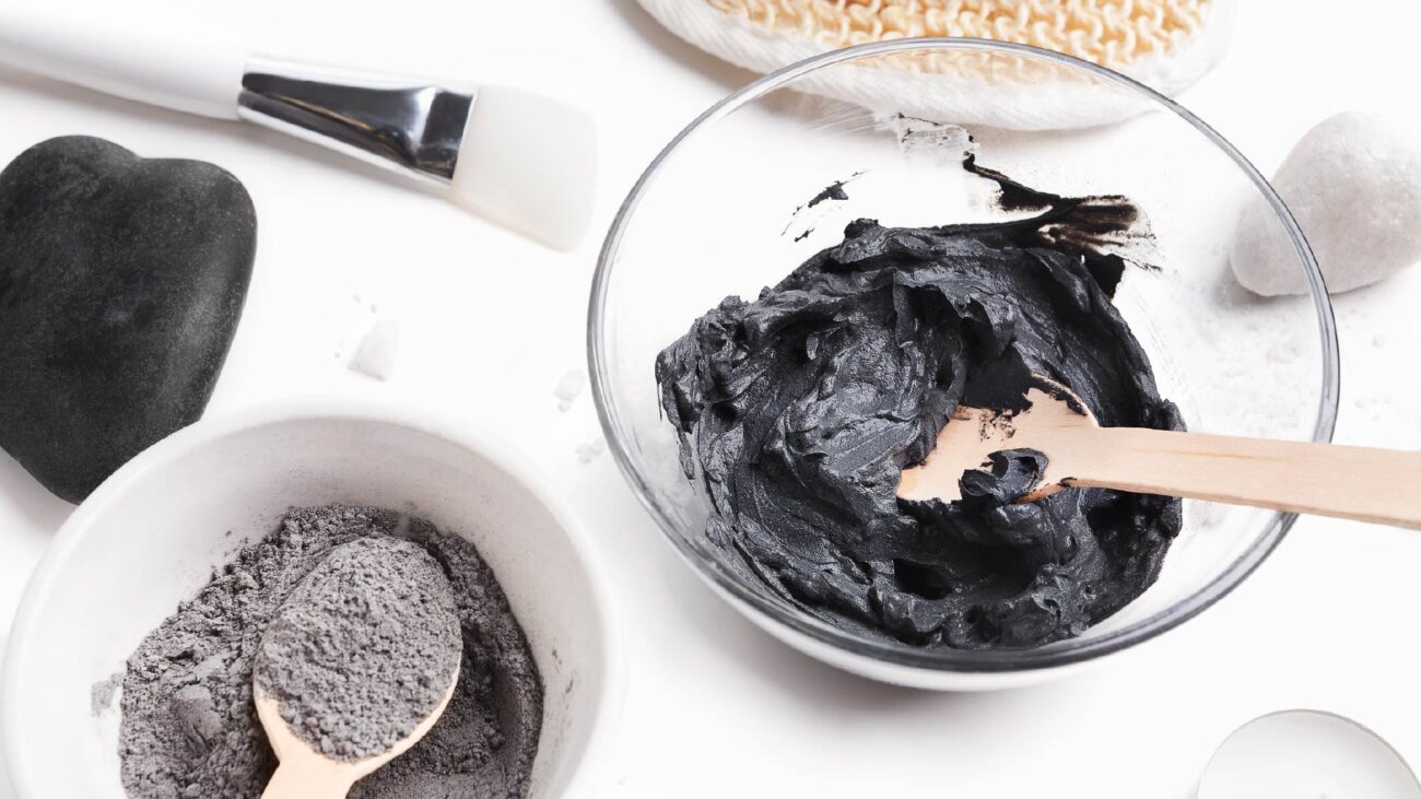 A bowl of grey powder and another bowl of a dark grey paste face mask.
