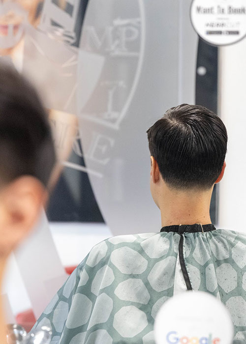 The back of a boys head in the reflection of a mirror in a barber shop in Bishop's Stortford.