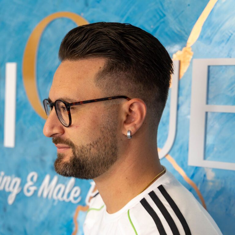 A mans side profile showing his skin fade in front of the Unique picture wall.