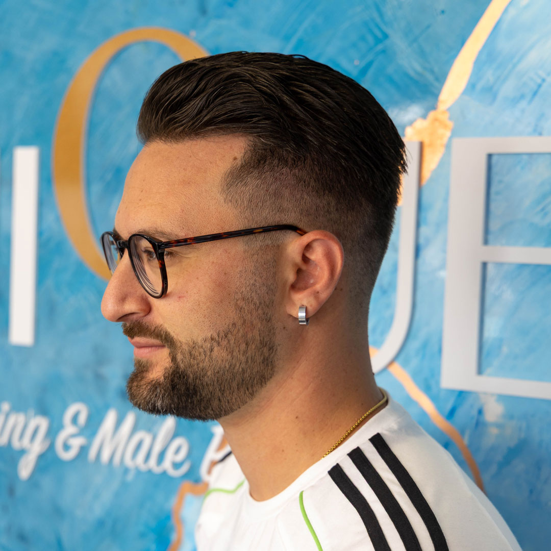 A mans side profile showing his skin fade in front of the Unique picture wall.