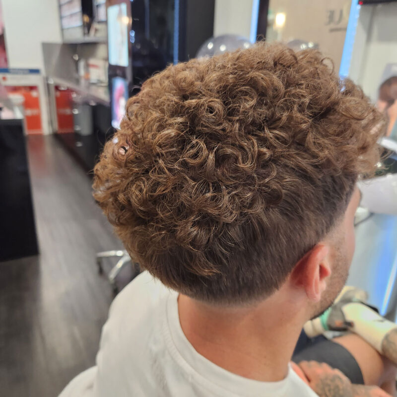 Back view of a mans head with a perm.