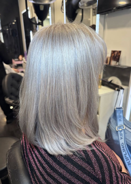 A woman sat in a salon chair with bright silver hair.