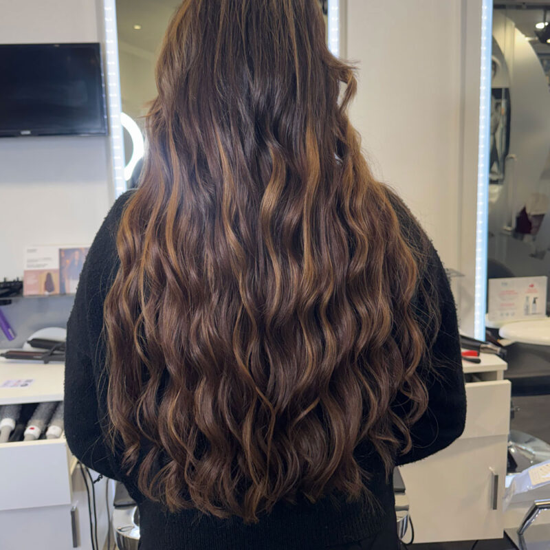 A girl's long brunette hair extensions at Unique hairdressing in Bishop's Stortford.