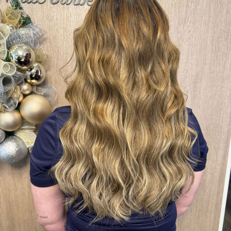 A girl's wavy blonde highlight hair extensions by Unique Hairdressing in Bishop's Stortford.