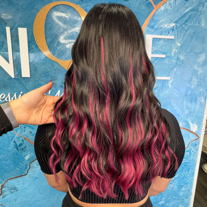 A girl with black hair and pink hair extensions at Unique Hairdressing.