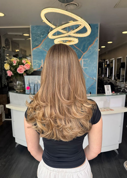 A girl has blonde highlights and a bouncy blow dry.